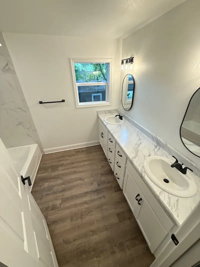 Finished bathroom with a white double vanity and wood-look floor