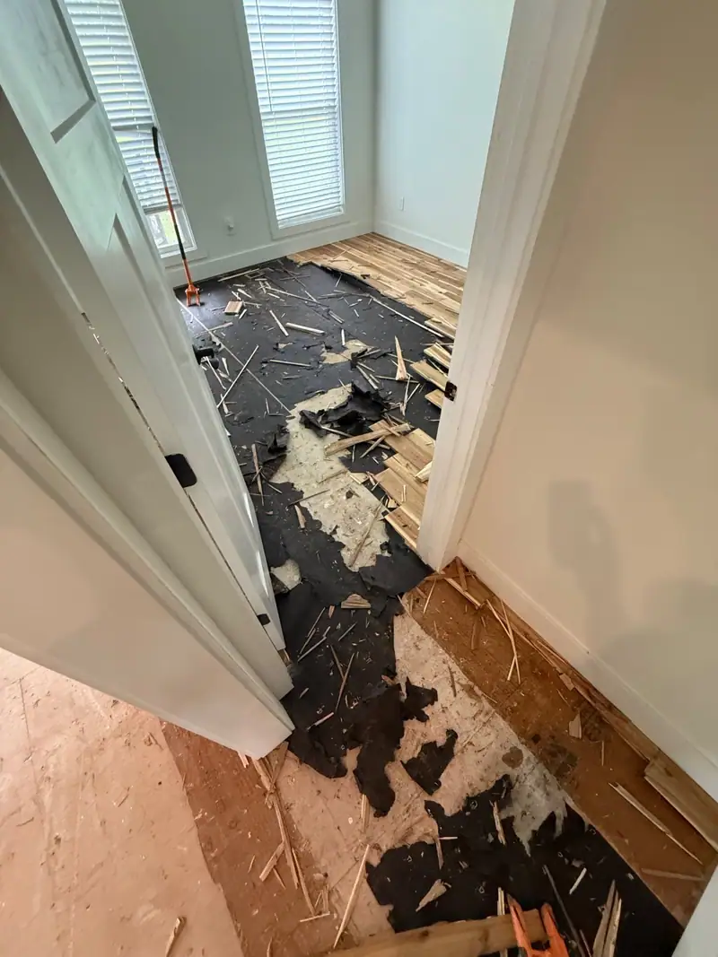 Wet hardwood flooring torn out down to the subfloor in a doorway